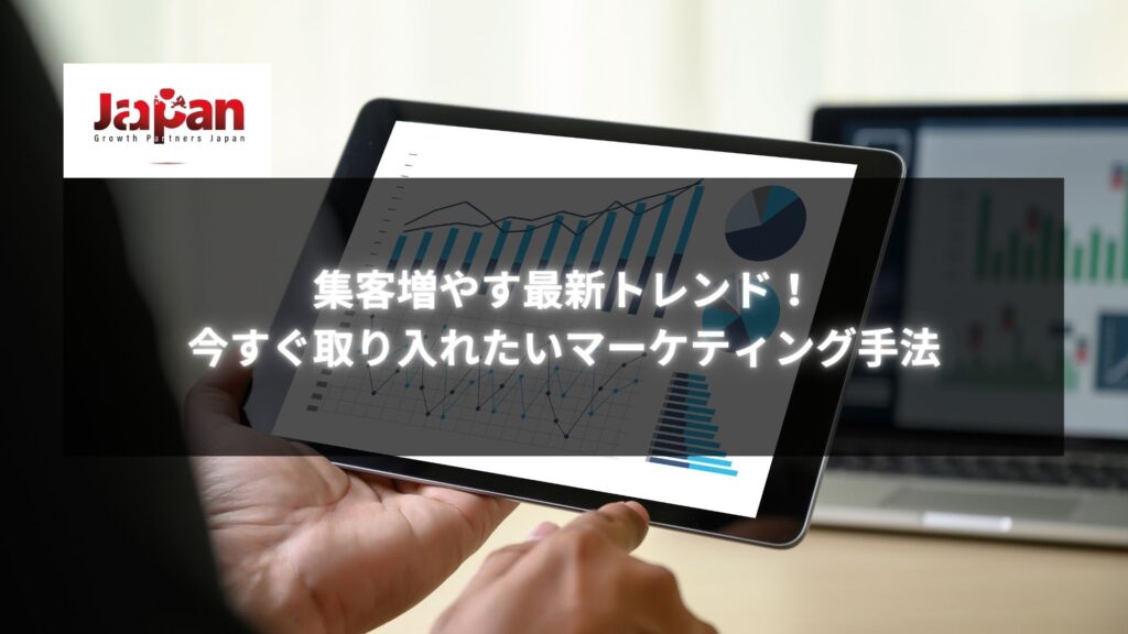 タブレットに表示されたグラフとチャートを操作する手の画像。「集客増やす最新トレンド！今すぐ取り入れたいマーケティング手法」というタイトルが記載されています。
