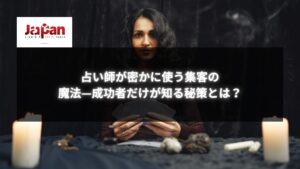 黒い背景でタロットカードを手にする占い師の女性とろうそく。占い師が集客方法について考えるイメージ。